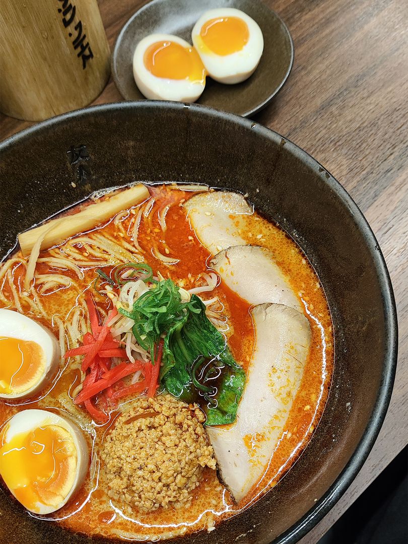 A bowl of ramen with chashu, egg and sprouts